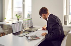 Male bookkeeper working with financial report in in office.