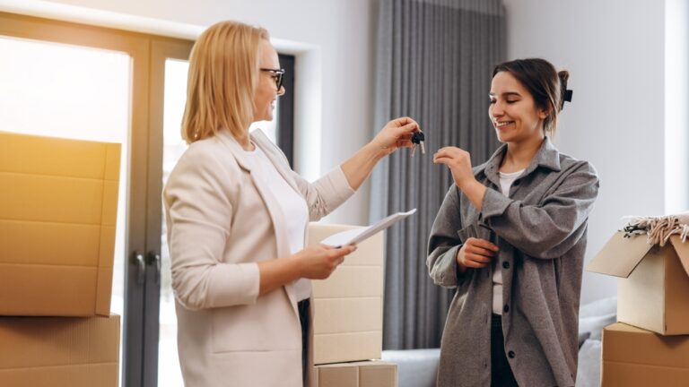 A smiling woman receives house keys from a real estate agent in a new home.